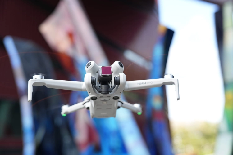 Zestaw 7 filtrów Freewell do DJI Mini 4 Pro – dron z filtrem w locie na tle kolorowej ściany
