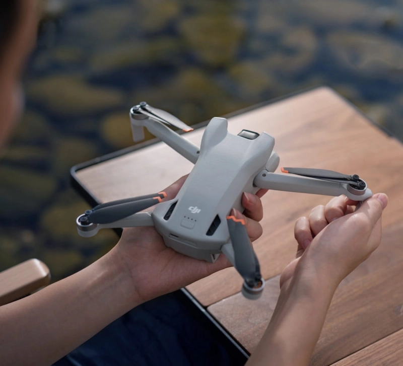 Dron DJI Mini 3 z kontrolerem RC w dłoni