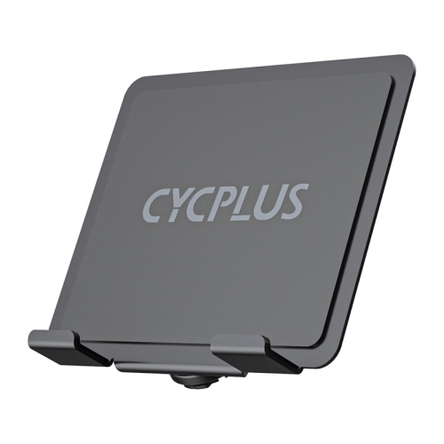 Kierownica roweru stacjonarnego z zamontowanym uchwytem Cycplus na duży tablet podczas treningu w pomieszczeniu.