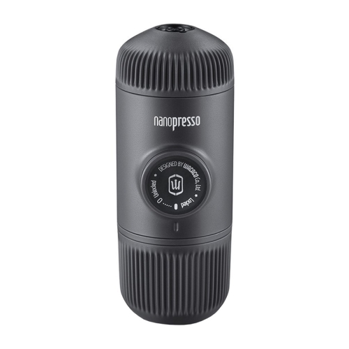 Kobieta przygotowująca kawę za pomocą przenośnego ekspresu Nanopresso na tle błękitnego nieba.