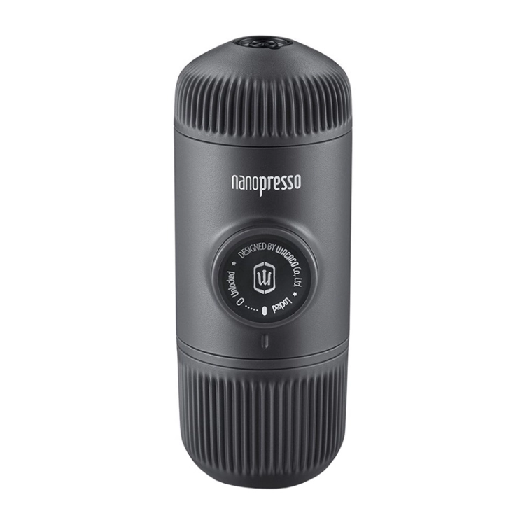 Kobieta przygotowująca kawę za pomocą przenośnego ekspresu Nanopresso na tle błękitnego nieba.