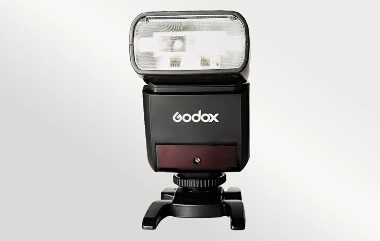 Godox TT350C na podstawce, widok z przodu na palnik i logo producenta