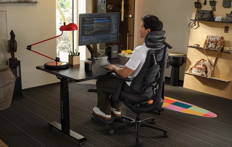 Mężczyzna pracujący przy komputerze na grafitowym krześle ergonomicznym LiberNovo Omni Pro