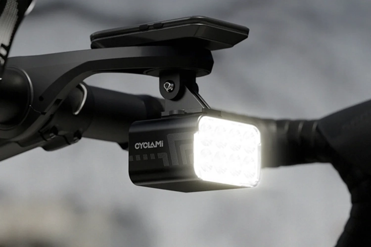 Włączona lampka CYCLAMI CYC1800 pod licznikiem na kierownicy szosowej