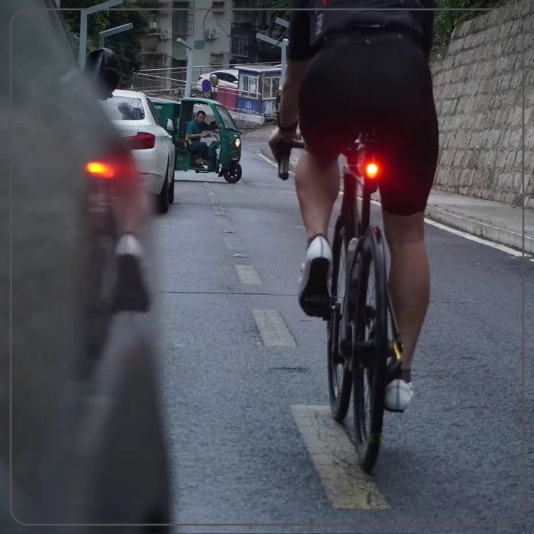 Rowerzysta z lampką CYCLAMI LA150 na drodze z samochodami z tyłu