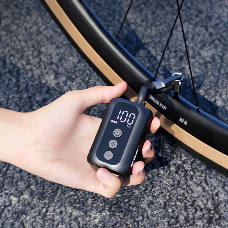 Pompka CYCLAMI A5S w dłoni przy wentylu koła gravelowego