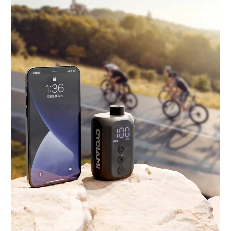 Pompka CYCLAMI A5S obok telefonu, w tle rowerzyści