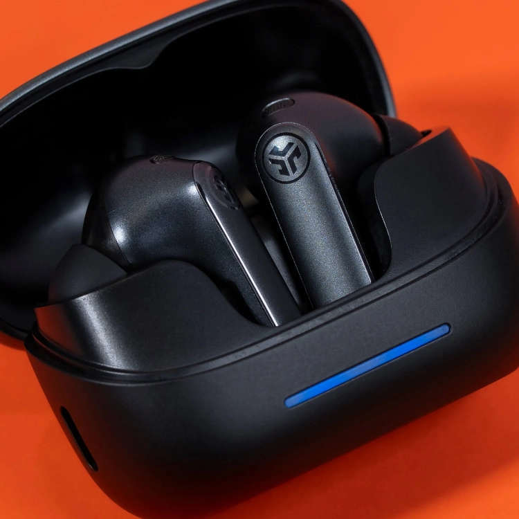 Otwarte etui JLab Epic Pods ANC z niebieską diodą na pomarańczowym tle