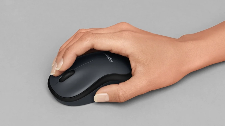 Dłoń na myszy Logitech M220 Silent obok klawiatury i notatek