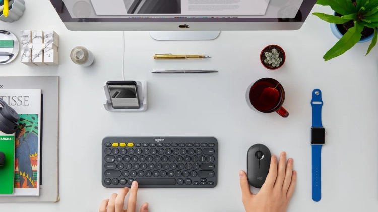 Grafitowa mysz Logitech Pebble M350 na biurku przy klawiaturze i laptopie
