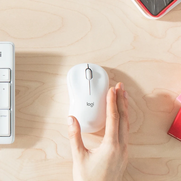 Biała mysz Logitech M221 Silent przy jasnej klawiaturze na biurku