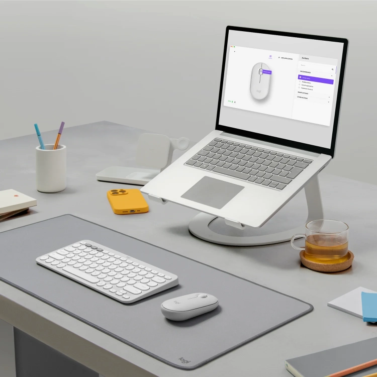 Biała Pebble Mouse 2 M350s na biurku z laptopem i słuchawkami