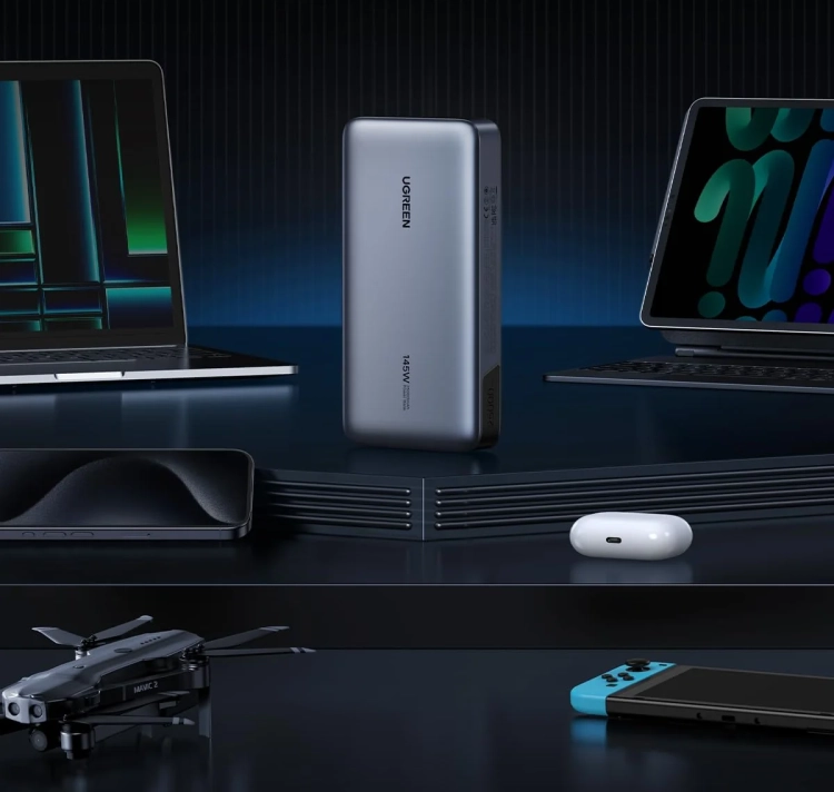 Powerbank UGREEN PB205 stojący na biurku obok tabletu i drona