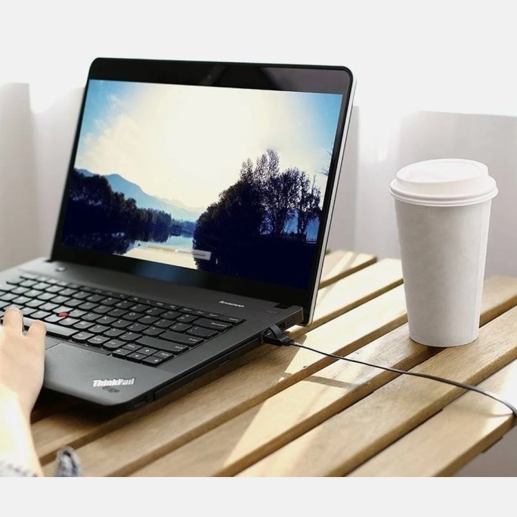 Kabel sieciowy UGREEN NW101 podłączony do laptopa na drewnianym stole