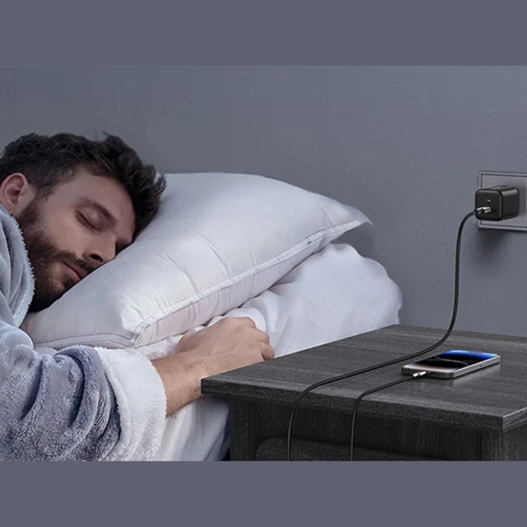 Ładowarka UGREEN X526 w gniazdku ładuje telefon na szafce nocnej