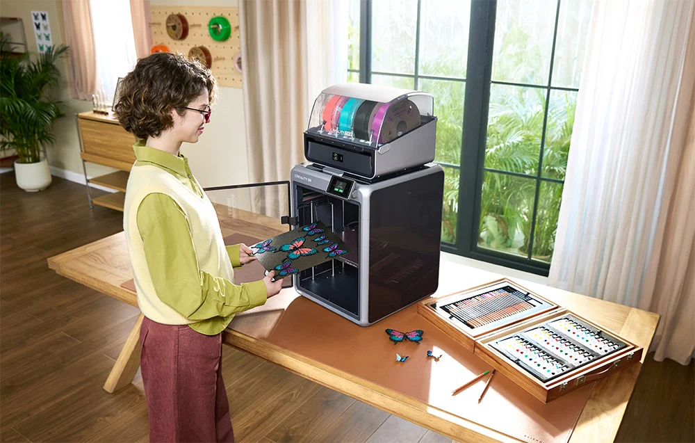 Uśmiechnięta kobieta drukuje modele 3D za pomocą drukarki Creality K2 Combo w jasnym pomieszczeniu.