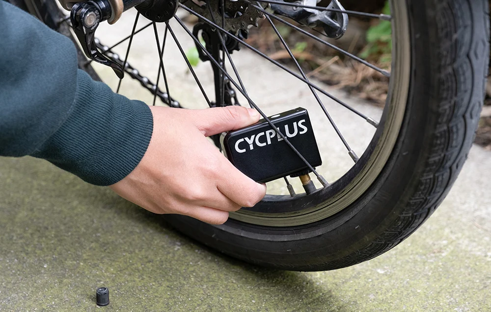 Proces pompowania opony roweru na świeżym powietrzu przy pomocy pompki akumulatorowej Cycplus AS2.