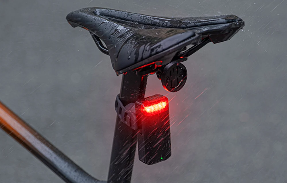 Tylna lampka rowerowa Cycplus zamontowana na prętach siodełka, odporna na intensywne opady deszczu.