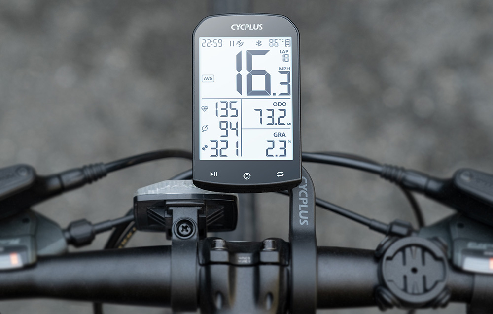 Nowoczesny komputer rowerowy Cycplus M1 z dużym ekranem zamontowany na kierownicy roweru szosowego.