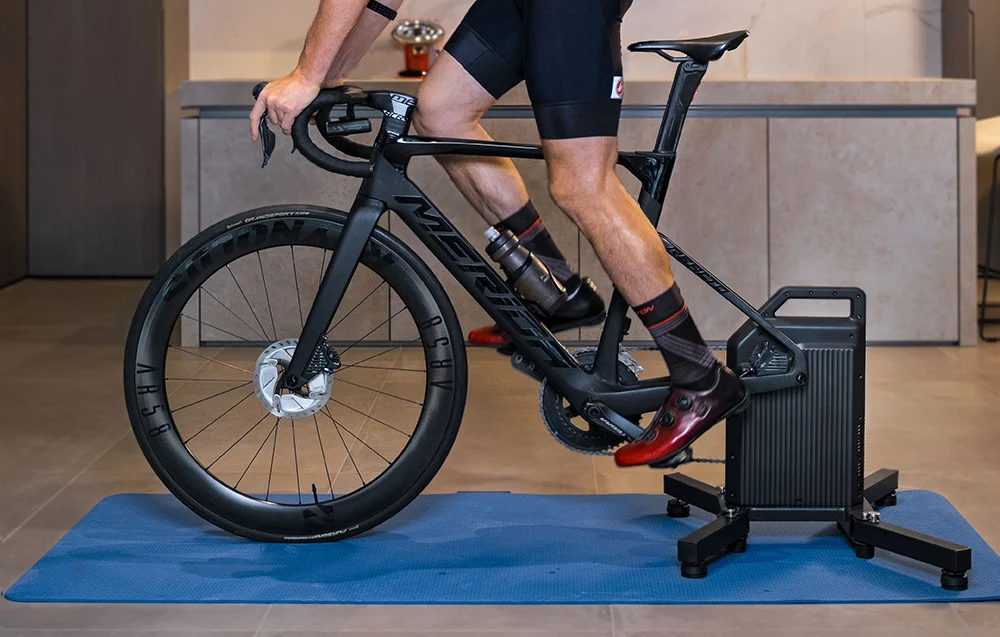 Kolarz szosowy realizujący plan treningowy na rowerze wpiętym w profesjonalny trenażer Cycplus T2.