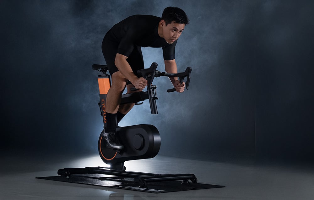 Mężczyzna trenujący na profesjonalnym rowerze stacjonarnym Cycplus Smart Bike T7.