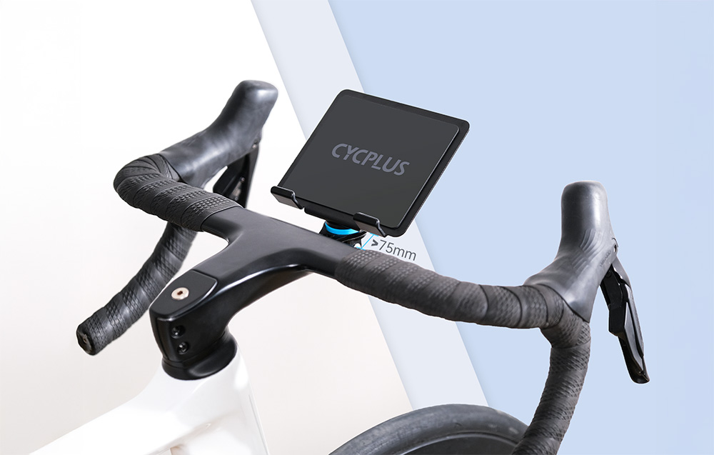 Kierownica roweru stacjonarnego z zamontowanym uchwytem Cycplus na duży tablet podczas treningu.