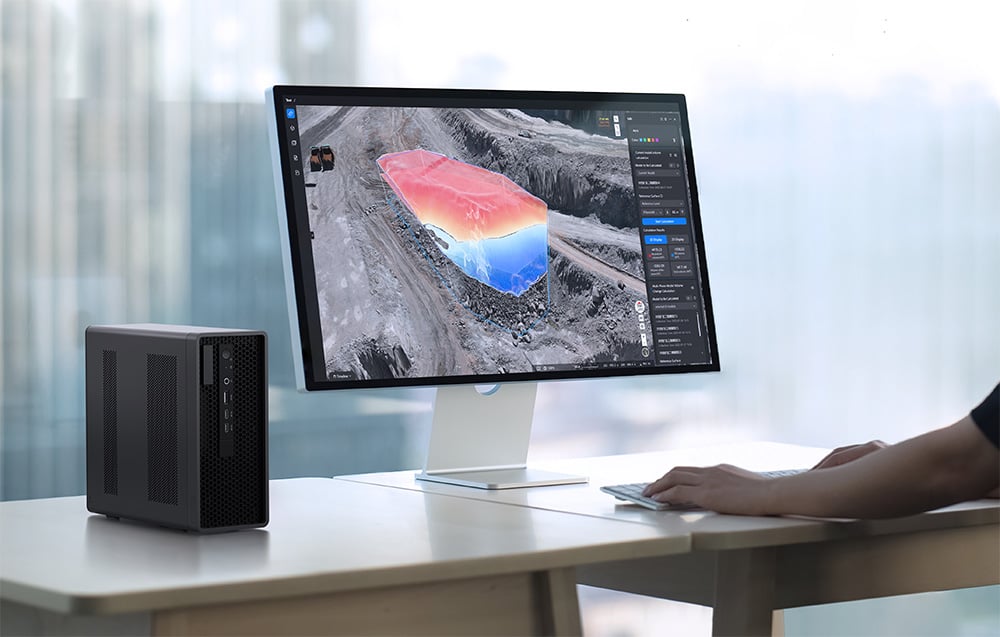 Monitor z trójwymiarową mapą terenu obok kompaktowego komputera na biurku