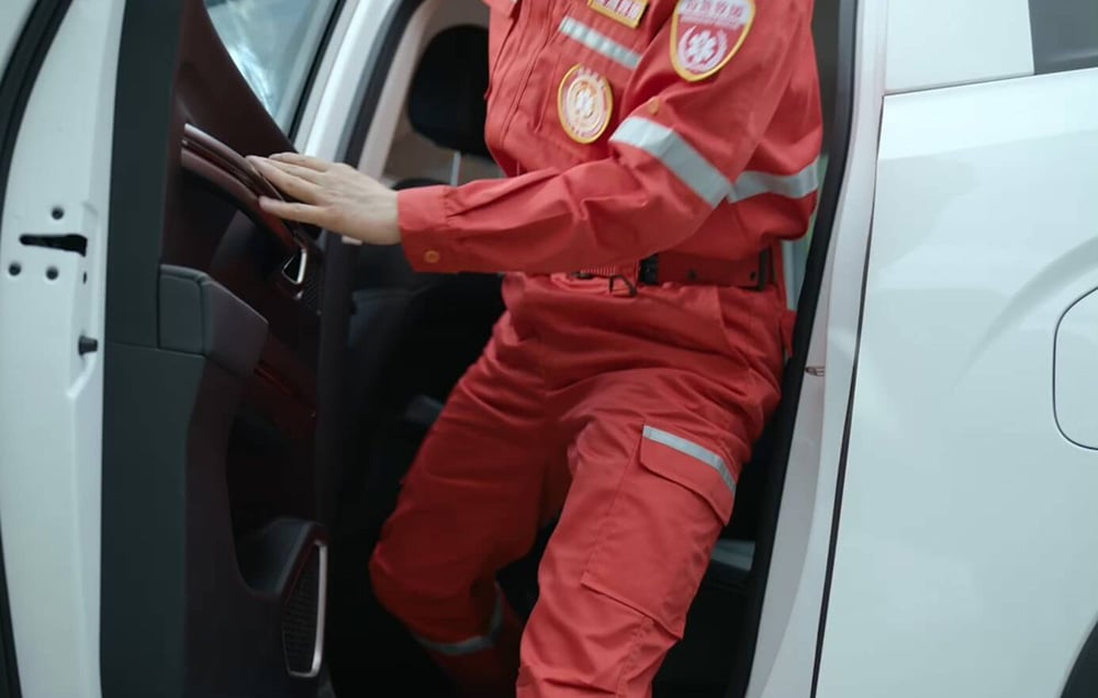 Ratownik w czerwonym kombinezonie wychodzący z pojazdu w trakcie akcji terenowej