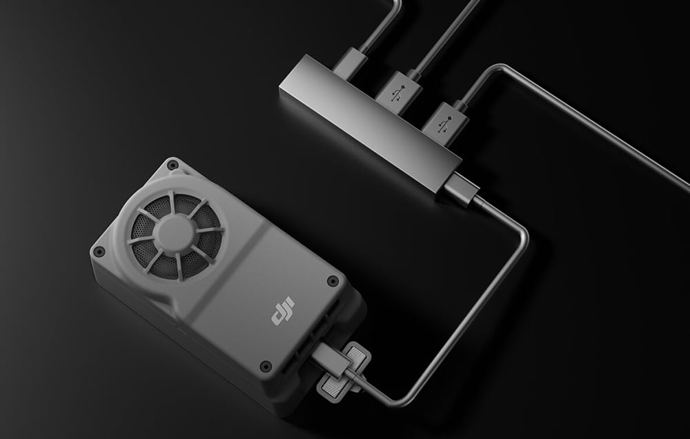 komputer pokładowy do dronów DJI podłączony do koncentratora USB z trzema kablami, na czarnym tle