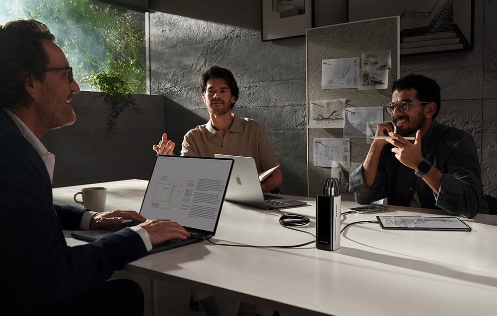 Trzech mężczyzn pracuje przy laptopach podczas spotkania biznesowego w nowoczesnym biurze