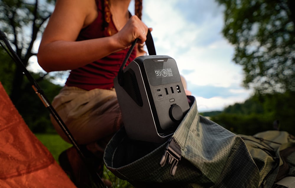 Kobieta wkłada przenośną stację EcoFlow TRAIL 300 DC do plecaka turystycznego w lesie