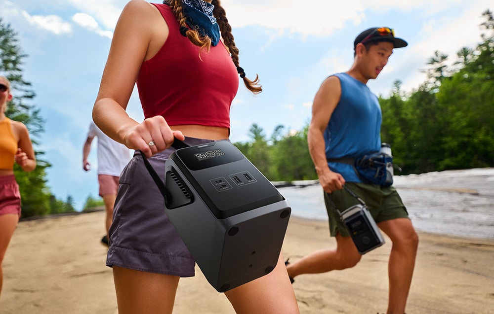 Kobieta niesie stację EcoFlow TRAIL 200 DC za uchwyt podczas wędrówki z grupą