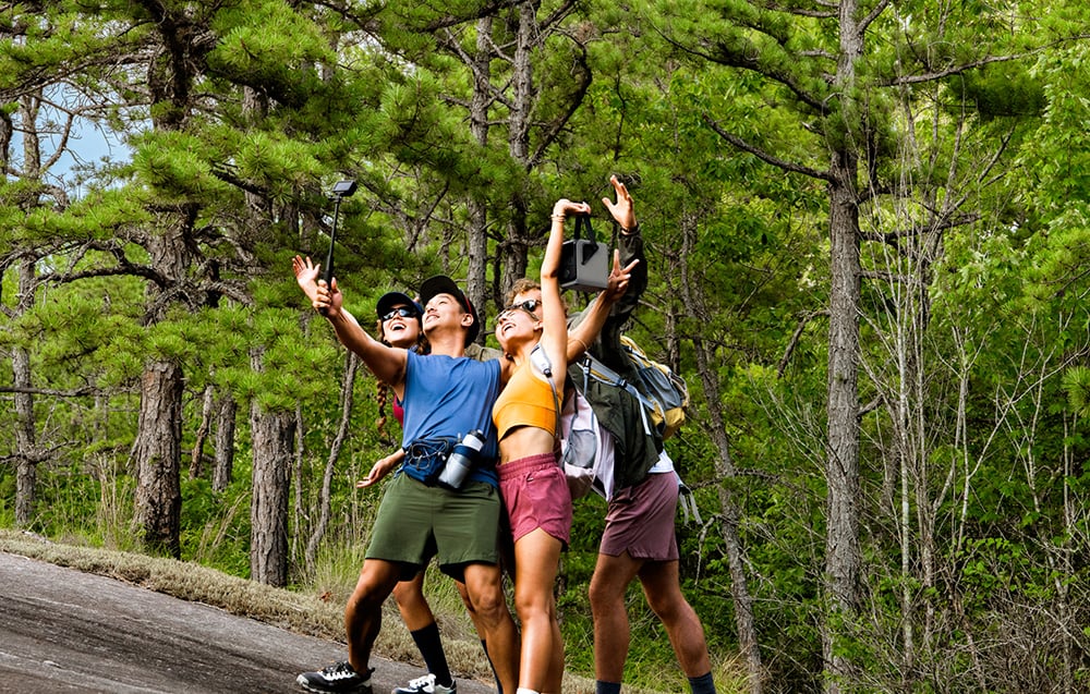 Trzy osoby robią wspólne zdjęcie trzymając nad sobą EcoFlow TRAIL 200 DC w lesie
