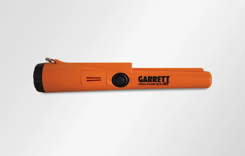 Ręczny wykrywacz metali Garrett Pro-Pointer AT wyposażony w miarkę, skrobak z twardego plastiku i pomarańczową wodoszczelną obudowę.
