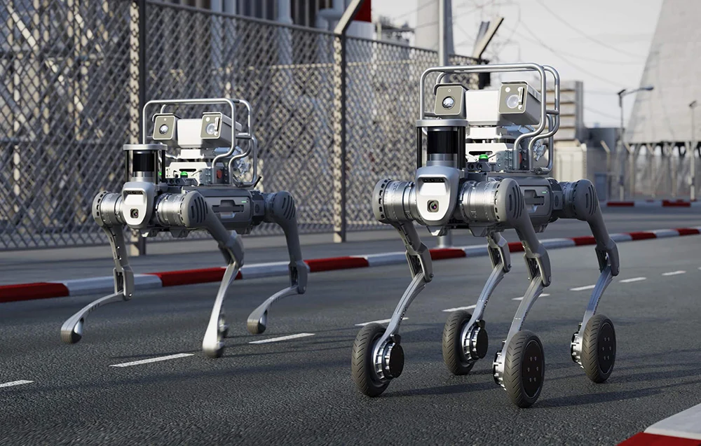 Dwa roboty Unitree B2-W z LiDARem na ulicy przy obiekcie przemysłowym – zastosowania logistyczne, inspekcyjne i R&D.