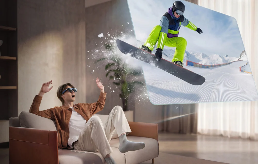 Mężczyzna w okularach AR siedzi na kanapie, obserwując wirtualny obraz osoby na desce snowboardowej.