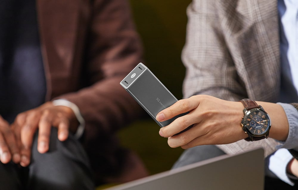 Osoba trzymająca translator TIMEKETTLE X1 podczas rozmowy w innym języku