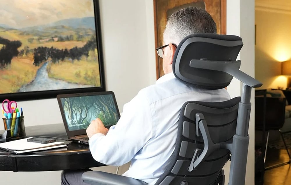 Osoba korzystająca z laptopa na krześle LiberNovo Omni Dynamic widziana od tyłu