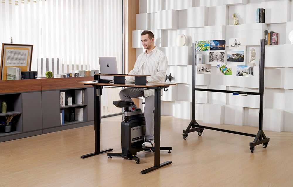 Mężczyzna pracujący przy laptopie na rowerze treningowym KINGSMITH EBW18 W1B