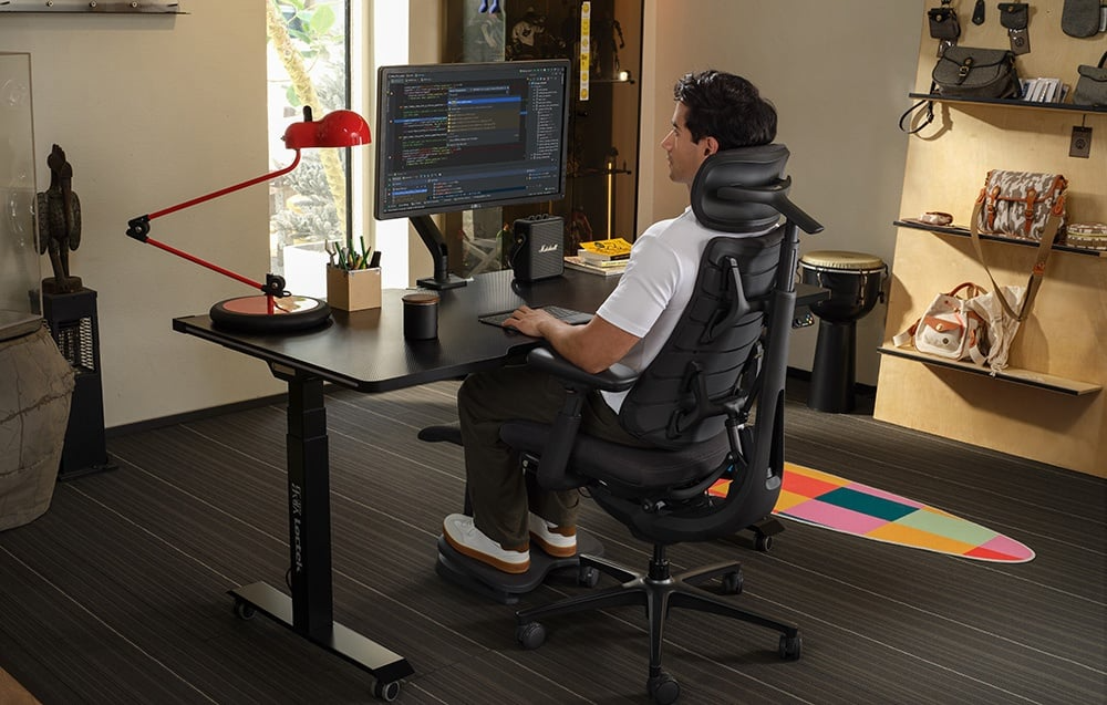 Mężczyzna pracujący przy komputerze na grafitowym krześle ergonomicznym LiberNovo Omni Pro 48 cm