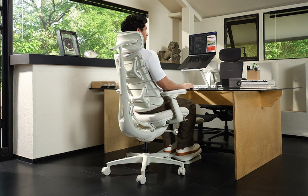 Osoba korzystająca z laptopa na białym krześle LiberNovo Omni GEN 45 cm