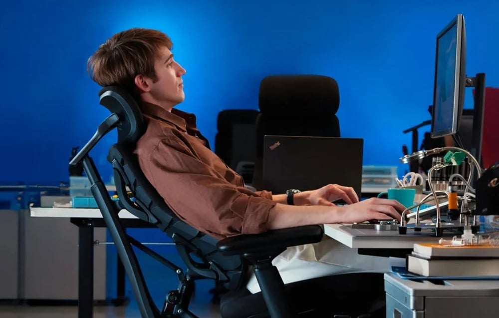 Mężczyzna pracujący przy komputerze na czarnym krześle ergonomicznym LiberNovo Omni SE