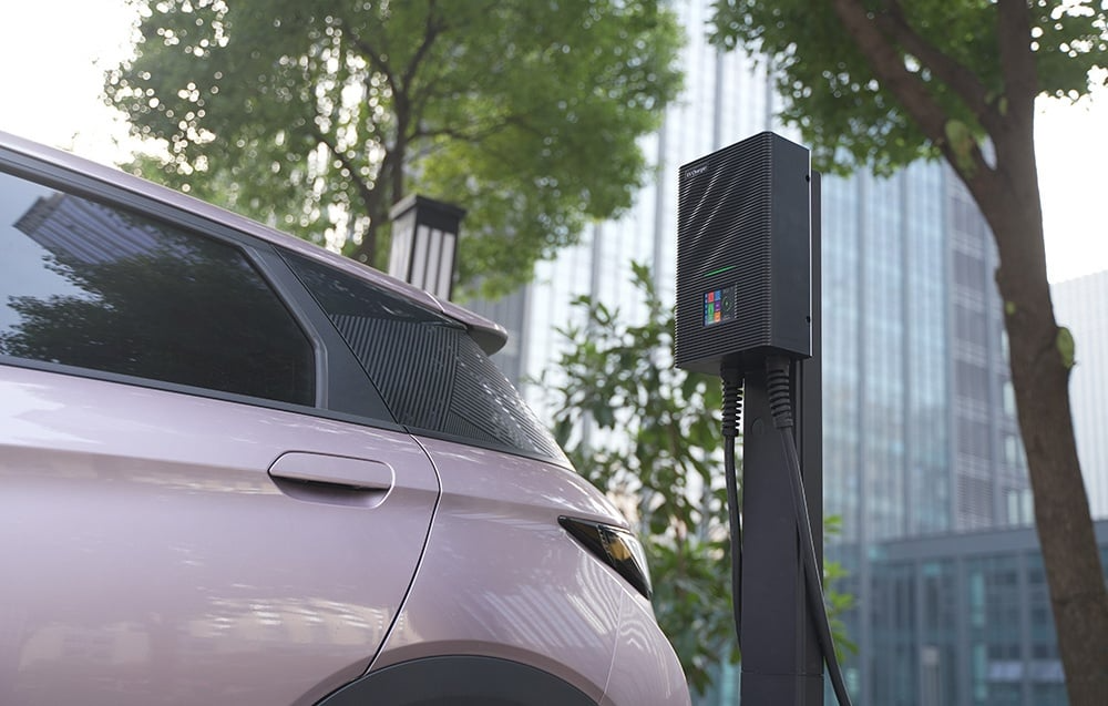 Samochód elektryczny podłączony do ładowarki BESEN SQW45 przy budynku