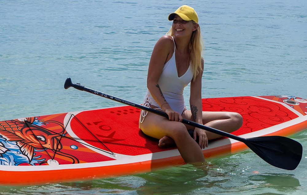 Kobieta siedząca na desce SUP FunWater Feath-R Lite Koi z wiosłem