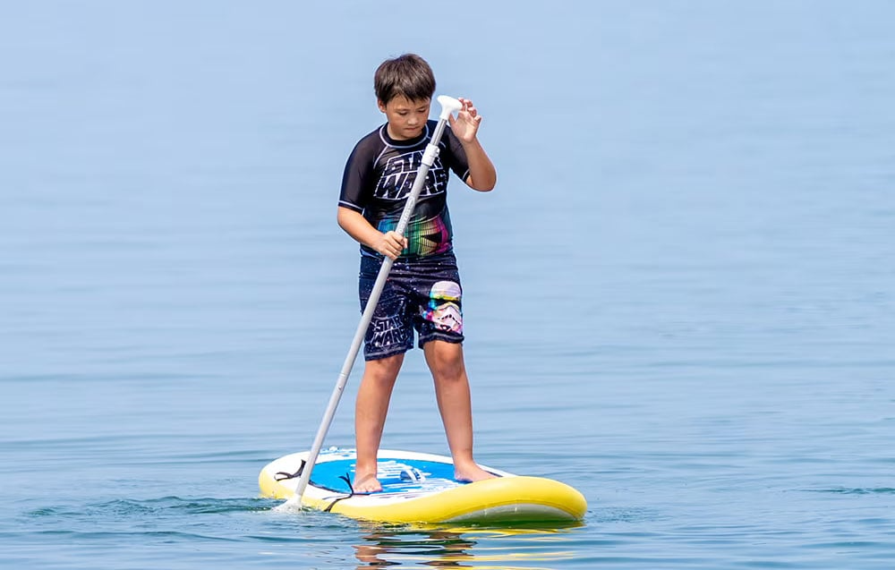 Chłopiec pływający na desce SUP FunWater Tuxedo Sailor z wiosłem